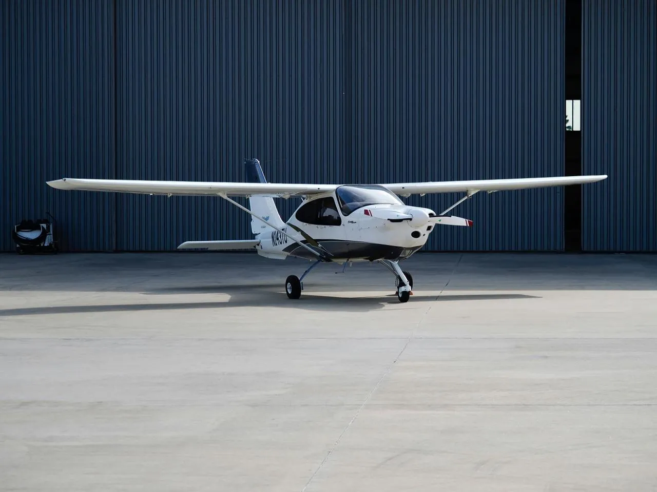 Light aircraft parked in front of a hangar