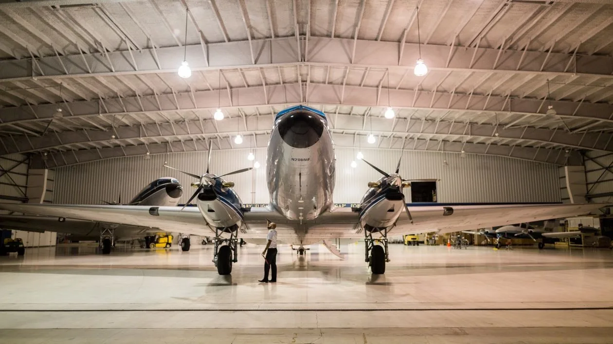 An aircraft parked overnight inside a lit hangar