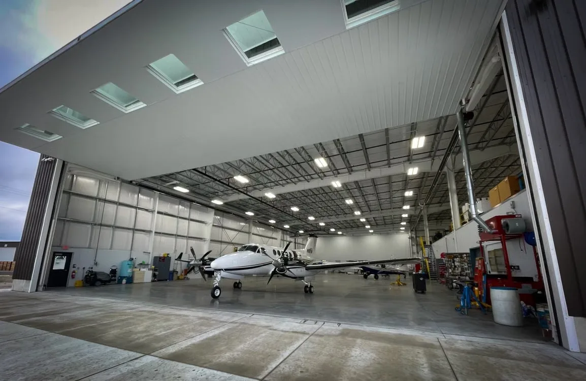 A private hangar with its door open at dusk