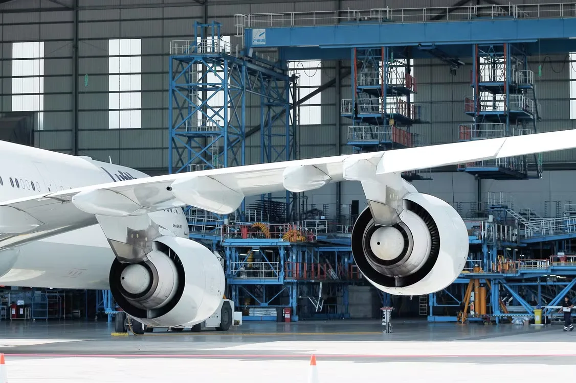 An aircraft under maintenance inside a working hangar